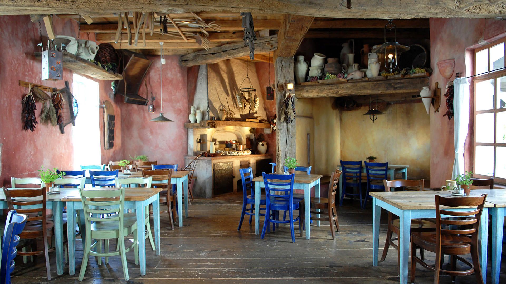 Raum in griechischem Stil mit bunten Steinwänden und Holzbalken.