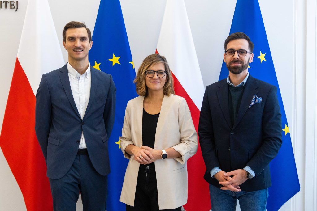 uczestnicy konferencji na tle flag Polski i Unii Europejskiej