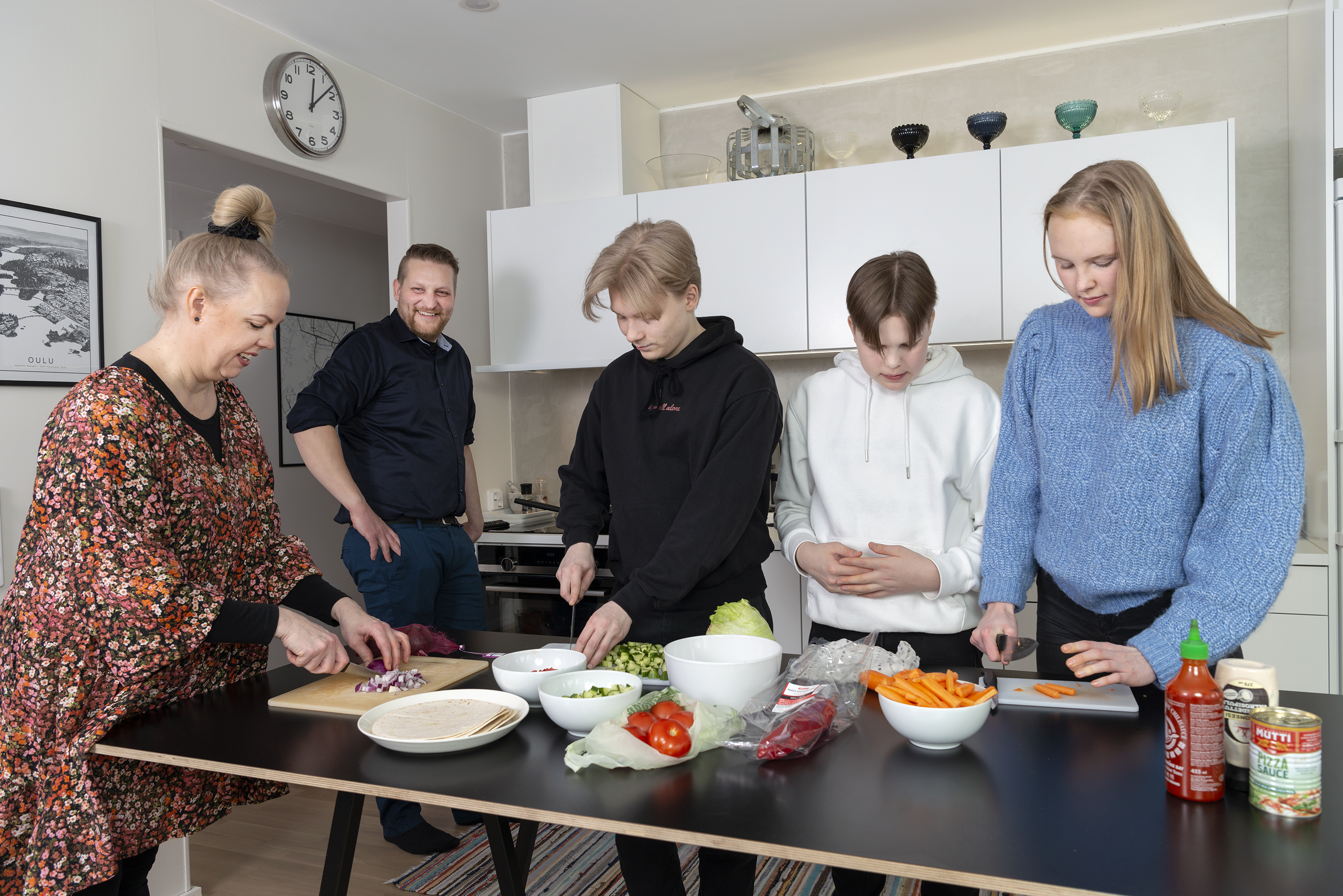 Perhe laittaa ruokaa keittiössä