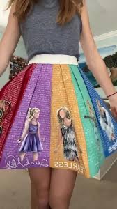 a young girl in a rainbowcolored skirt poses for the camera. she is smiling and looking at the camera. she is standing in an indoor setting.