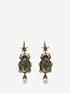 a pair of goldtone earrings featuring a scarab beetle pendant with iridescent abalone shell inlay, embellished with a star charm at the top and a dangling pearl at the bottom.