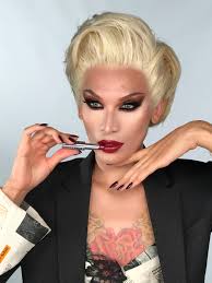 a closeup portrait of a drag queen with platinum blonde hair styled in a classic updo. she's wearing a black blazer over a patterned top, and applying dark red lipstick with a silver tube. her makeup is meticulously done, featuring winged eyeliner and dark eyeshadow, and she has visible floral tattoos on her chest.  the overall aesthetic is a blend of vintage glamour and modern high fashion. the image is sharp and welllit, suggesting a professional studio setting.