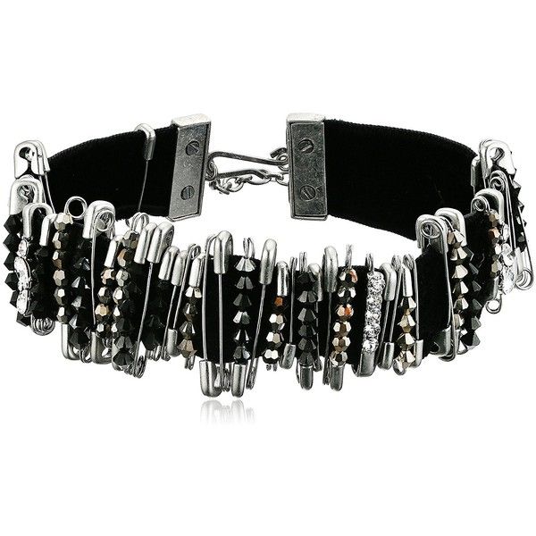 a closeup studio shot of a choker bracelet. the bracelet is made of black velvet and decorated with silver safety pins. the safety pins are adorned with various beads in black, silver, and clear colors. the bracelet has a silver clasp. the style is punk/gothic.