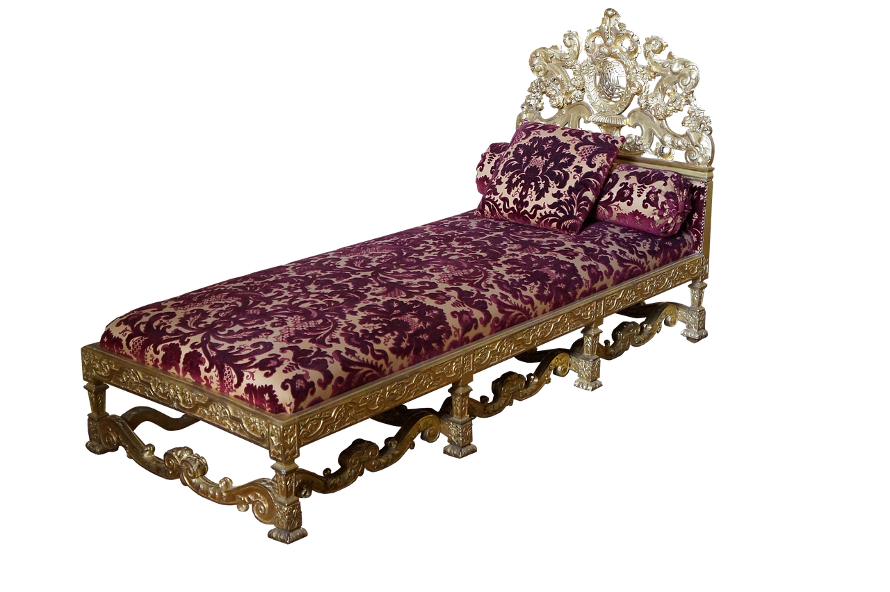 an ornate antique daybed with a gold frame and plush purple and gold floral patterned upholstery. the headboard is elaborately carved and gilded, with matching pillows. the bed frame has decorative legs and carvings. the background is a solid black.