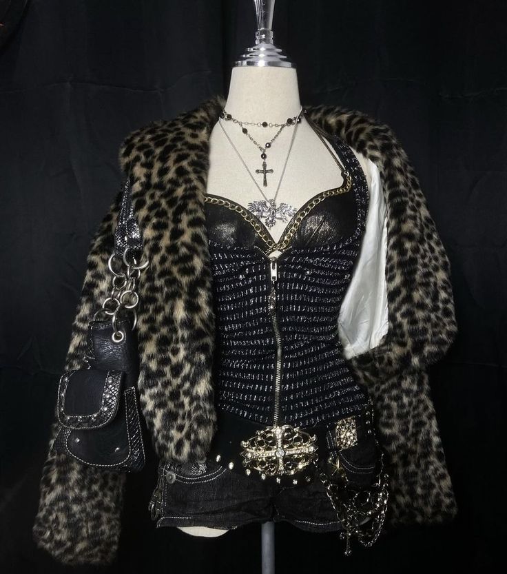 a fashion mannequin dressed in a stylish outfit.  the mannequin is wearing a leopard print fur coat, a black corset with silver and gold chains, black denim shorts with gold embellishments and a silver chain belt. the mannequin also has a black purse with silver chain hanging from the coat.  the mannequin is wearing several necklaces with silver and gold chains.