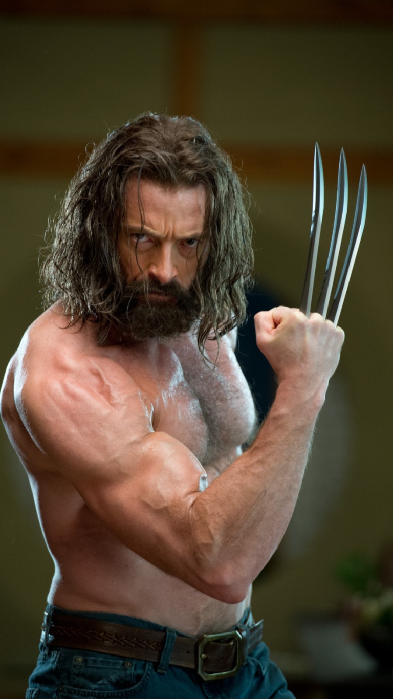 a closeup shot of hugh jackman as wolverine, shirtless with his signature claws extended. he has a thick beard and long, wet hair. his muscular build is prominently displayed. he is wearing jeans with a belt. the background is a neutral, slightly blurry interior.