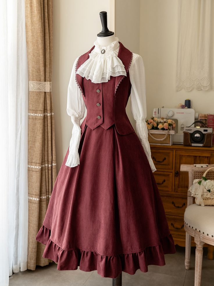 a fulllength view of a mannequin dressed in a burgundy lolita fashion dress. the dress features a flowing skirt with ruffles, a fitted vest, and a white highcollared blouse with lace detailing. the mannequin is positioned in a room with a window and furniture in the background.