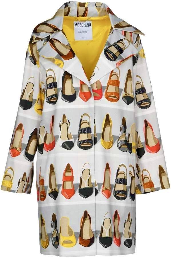a long, lightcolored coat patterned with illustrations of various highheeled shoes. the coat has a bright yellow lining.