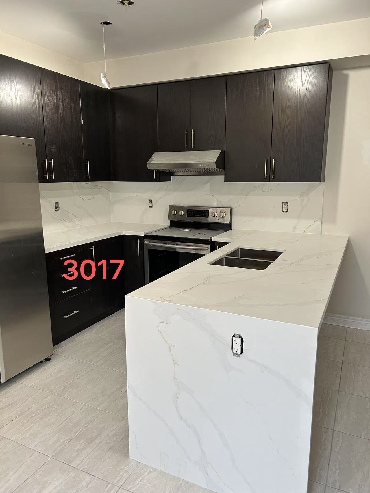 a kitchen with black cabinets, white marble countertops and a kitchen island.