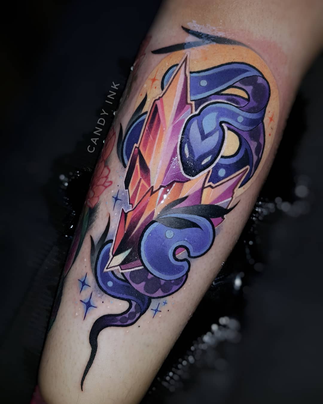 a colorful tattoo of a purple snake wrapping itself around a glowing crystal with a moon in the background. there are small yellow stars next to it.