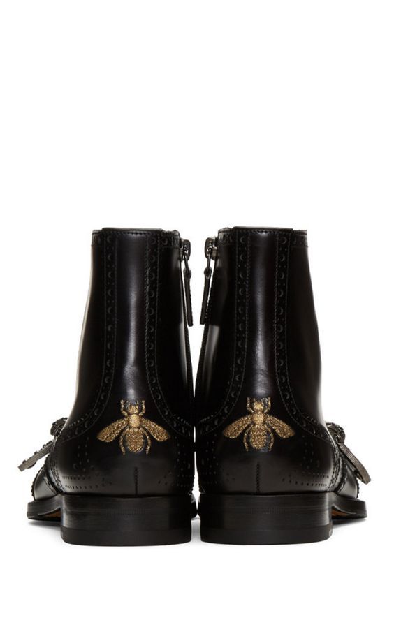 a pair of black leather women's ankle boots with gold embroidered bees on the sides. the boots are wingtip style with side zippers and have a slightly chunky heel.  they appear to be a designer brand, possibly gucci, given the bee motif. the boots are presented from a side angle, showing both boots.