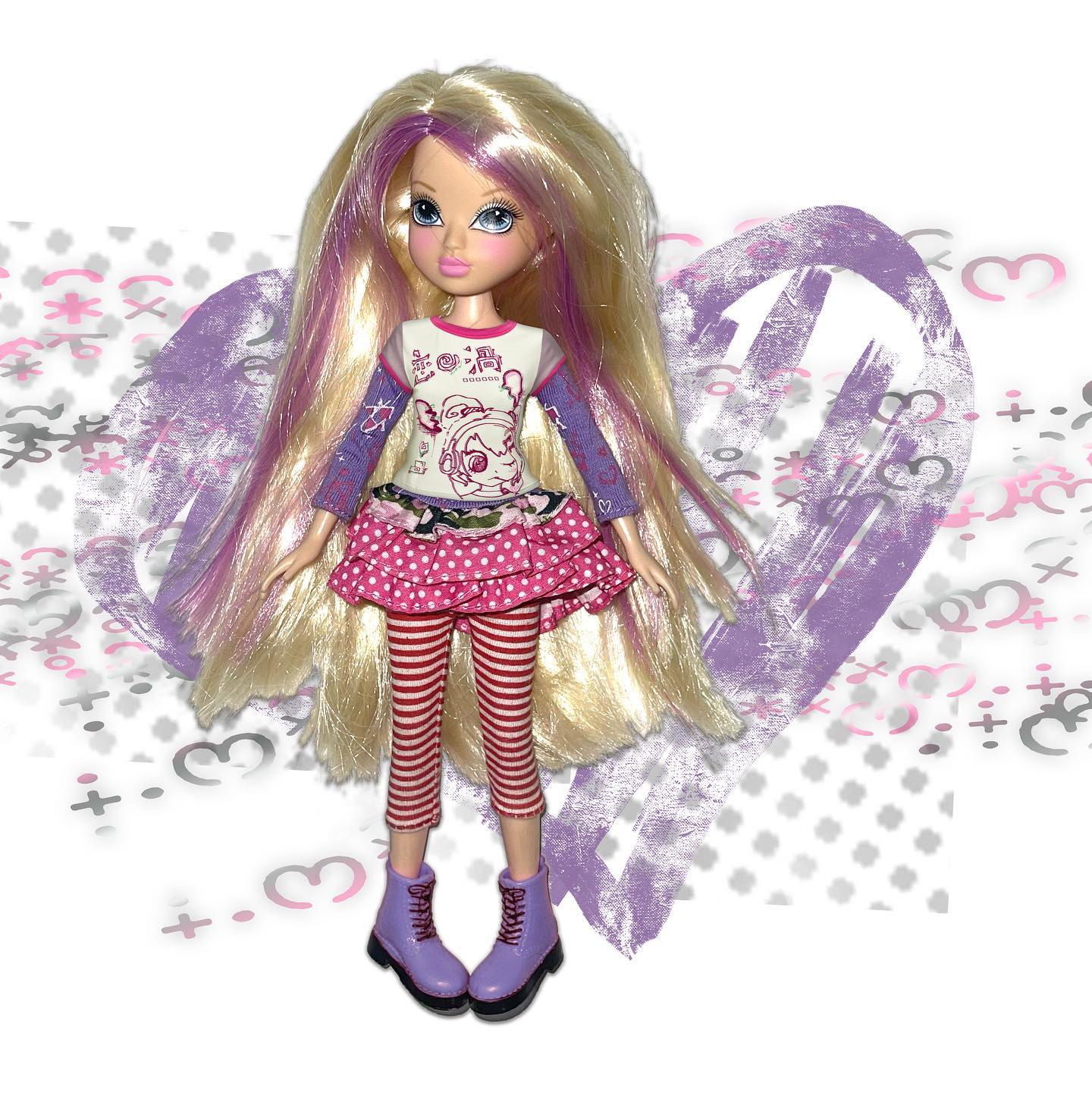 a bratz sasha doll with long blonde and purple streaked hair is shown against a background of painted hearts and graffiti. she wears a lavender longsleeved shirt with a pink and white polka dot ruffled skirt and striped leggings. her boots are purple.  the overall aesthetic is pastel and playful.