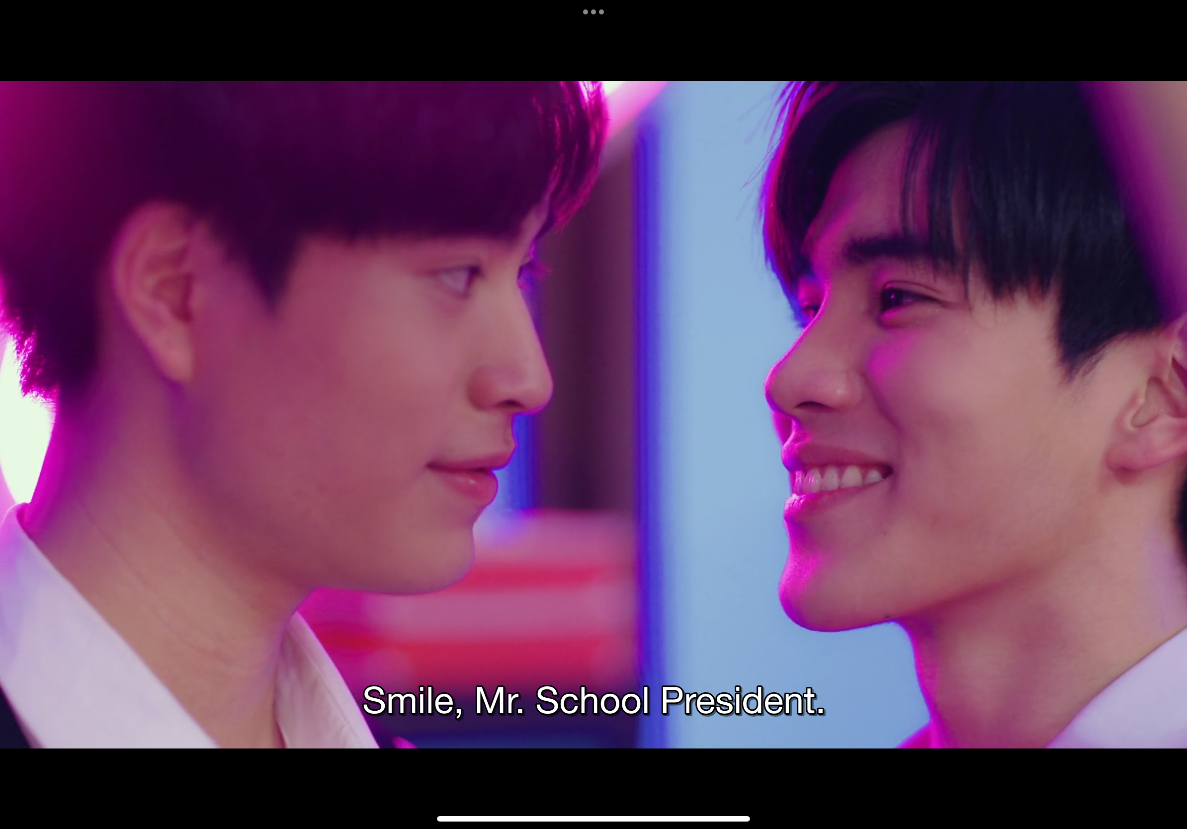 a screenshot from a thai bl (boys' love) drama, featuring two young men smiling at each other in what seems to be a club setting. the lighting suggests neon lights, creating a vibrant and romantic atmosphere. the text overlay, "smile, mr. school president", hints at a playful dynamic between the characters, possibly with one being the school president and the other addressing him.