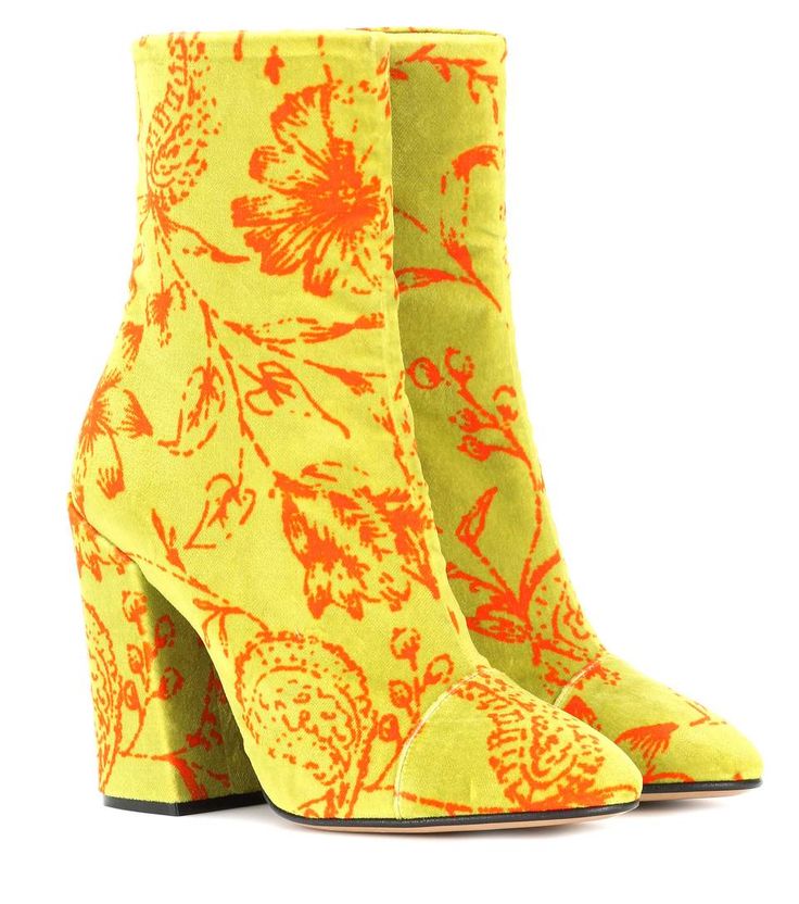 two yellow ankle boots with orange floral patterns are placed sidebyside against a white background. the boots have block heels and come up to the ankle.