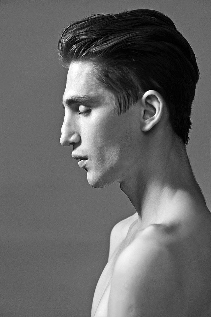 a black and white portrait of a young man, the subject is looking away from the camera. the man is wearing his hair slicked back, and his face and shoulders are visible. the subject has a serious expression. the photo was taken in a studio setting.