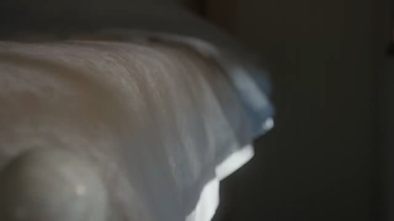 a closeup shot of a bed with white sheets. the sheets are wrinkled and the light is coming from the left side of the image, casting shadows on the right side.