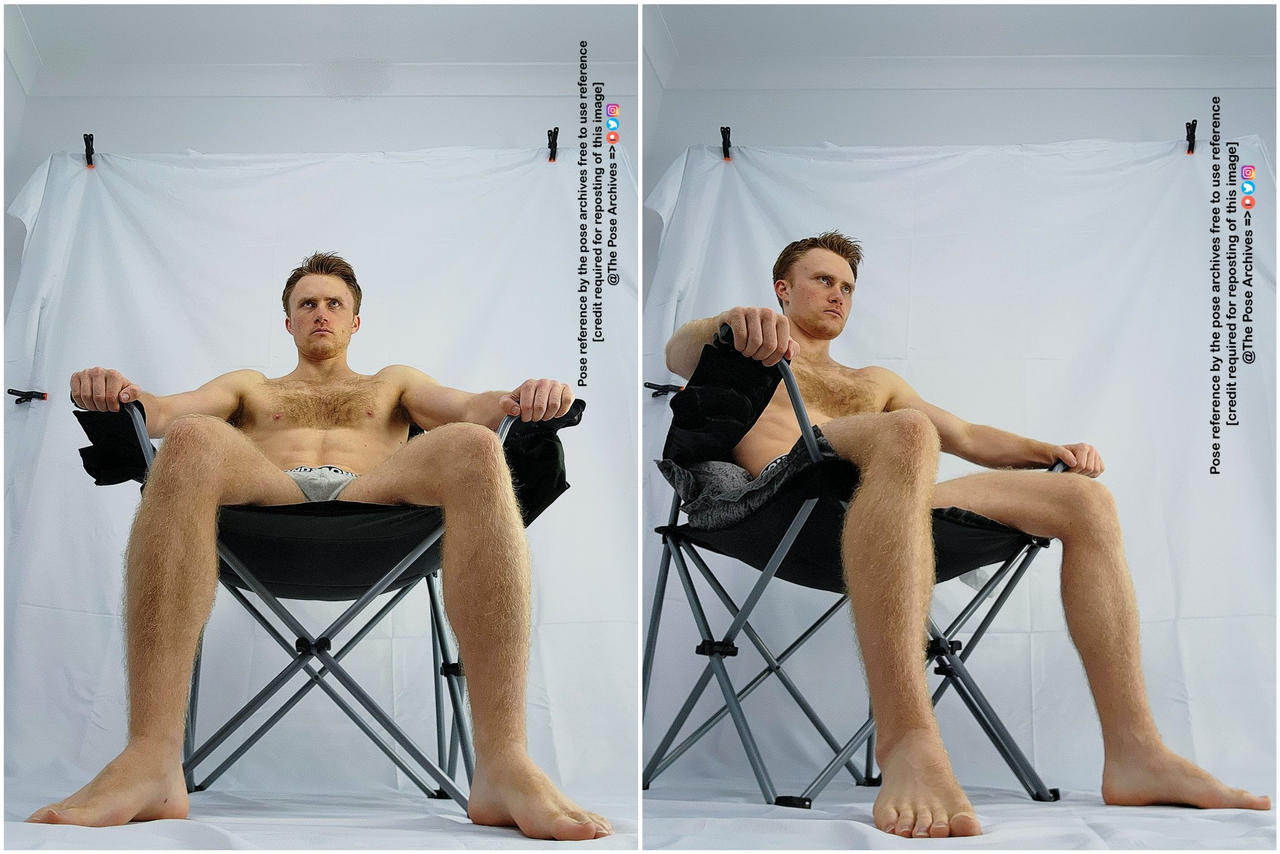 a shirtless man is sitting on a folding chair in front of a white backdrop. he is holding the arms of the chair and looking straight ahead. the image is a pose reference.