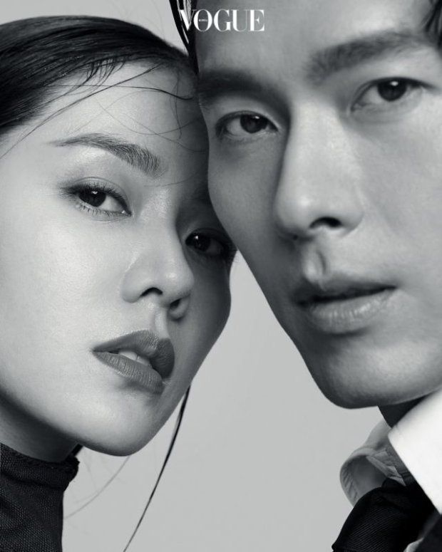 a black and white portrait of a man and a woman, both models,  looking at each other. the man is handsome with sharp features and a strong jawline. the woman is beautiful with soft features and long hair. they are both dressed in elegant fashion, and the image has a romantic and intimate feel. they appear to be a couple,  and the image evokes feelings of love and affection. it is likely a photo from a magazine, possibly vogue, as "vogue" is visible in the image.
