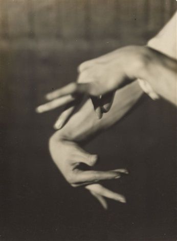 a black and white photograph of a person's hands, taken from a closeup perspective. the hands are intertwined, with the fingers interlaced in a complex and abstract pose. the photograph is shot in a dark studio setting, with only the hands illuminated, creating a dramatic and mysterious feel. the lighting emphasizes the contours and lines of the hands, highlighting the intricate beauty of the human form. the image is both anatomical and artistic, inviting viewers to contemplate the meaning and symbolism behind the gesture.