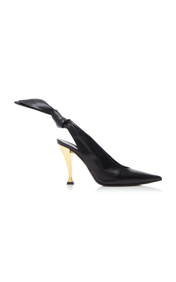 a pair of black leather pumps with a gold heel and a pointy toe. the shoes are slingbacks with a strap that wraps around the ankle and ties into a bow. the shoes are on a white background.