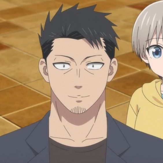 a closeup shot of a male anime character. he has dark hair, styled with a shaved undercut, and a goatee. he has tanned skin and appears expressionless. he is wearing a dark blue/black collared shirt with a black undershirt. another character, with short silver hair and wearing a yellow hoodie, is visible in the background on the right side of the image. the setting appears to be indoors, with a soft light source.