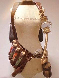 a steampunkinspired costume piece, a brown leather belt with various attachments, is displayed on a mannequin. the belt features multiple potion bottles filled with colorful liquids and dried flowers. other attachments include a miniature lantern, a gas mask component, and a pouch. the overall aesthetic leans towards a vintage, industrial, victorianera steampunk style.