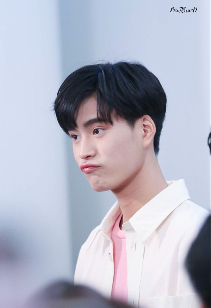 a portrait of a young asian man with black hair wearing a white overshirt and a pink undershirt. the background is white. he has a playful, pouty expression on his face. the lighting suggests a studio setting.  the image is a closeup, focusing on his head and shoulders.