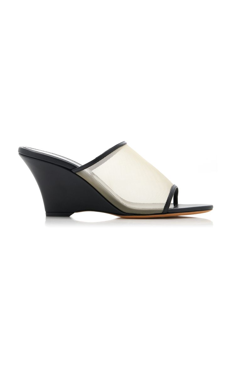 the image shows a pair of women's black leather wedge sandals.  the sandals have a mesh upper that is mostly transparent, revealing the wearer's foot. the wedge is black leather and the sole appears to be a light tan/beige color.  the sandals are presented against a white background, suggesting a product shot for online retail. the style is minimalist and chic.