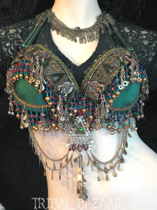 a closeup shot of a woman wearing a lavish, intricately beaded belly dancing bra. the bra is adorned with turquoise, green, gold and silver beads, sequins, and intricate details.  it is a true testament to the artistry and craftsmanship involved in creating traditional belly dancing costumes.
