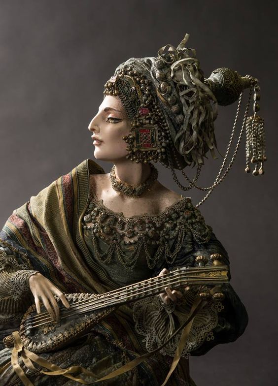 a portrait of a woman in ornate traditional clothing and jewelry, playing a stringed instrument similar to a lute. she is shown in profile, facing left, with an elaborate headdress and a draped shawl over her shoulders. her dress is heavily decorated with embroidery and beads, and she wears a necklace. the background is a muted gray, emphasizing the details of her attire and the instrument.