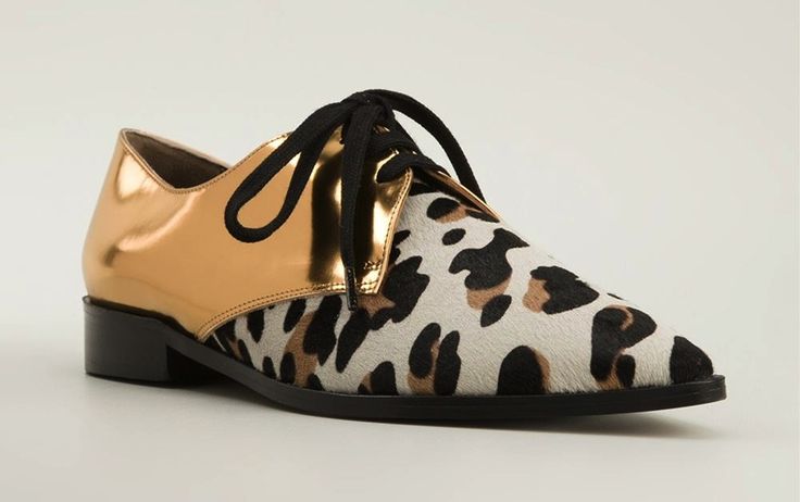 loseup shot of a pair of women's oxfords. the shoes are a unique blend of gold metallic leather on the front and a leopardprint calf hair on the back.  they have black laces and a pointed toe. the shoes are presented on a white background, highlighting their details.