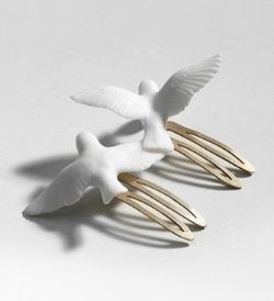 the image shows two birdshaped hair clips on a white surface. the birds are white and appear to be made of porcelain. they are attached to goldcolored hair clips. one bird is slightly above the other.