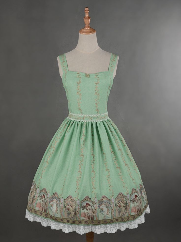 the image shows a green vintagestyle lolita dress on a mannequin. the dress is sleeveless with a square neckline and a midi length. it features a floral print with a border of lace trim at the hem. the dress is photographed against a gray background.