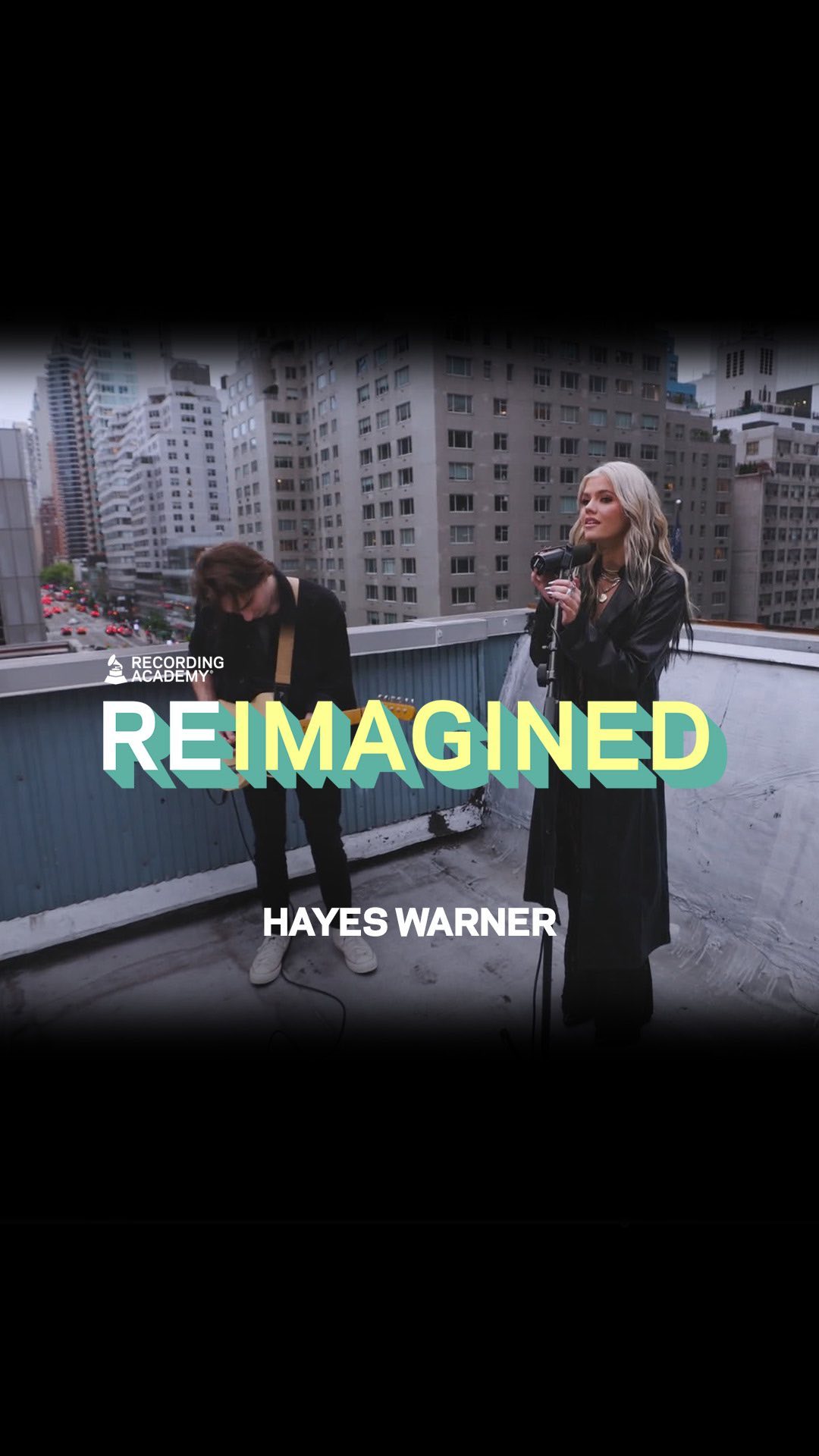 two musicians, a female singer and a male guitarist, are performing on a rooftop against the backdrop of city buildings. the image includes the words "reimagined" and "hayes warner," along with the recording academy logo, suggesting it's a music performance for a program or event. the singer is holding a microphone and the guitarist is playing the guitar.