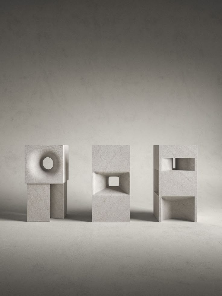 three abstract concrete sculptures stand in a row against a plain, neutral background. each sculpture has a unique geometric design with hollow openings. the sculpture on the left features a circular opening and a vertical base. the middle sculpture has a squareshaped opening with beveled edges. the sculpture on the right has a rectangular opening on top and an open space at the bottom. the overall image is minimalist and focuses on the shapes and textures of the sculptures.