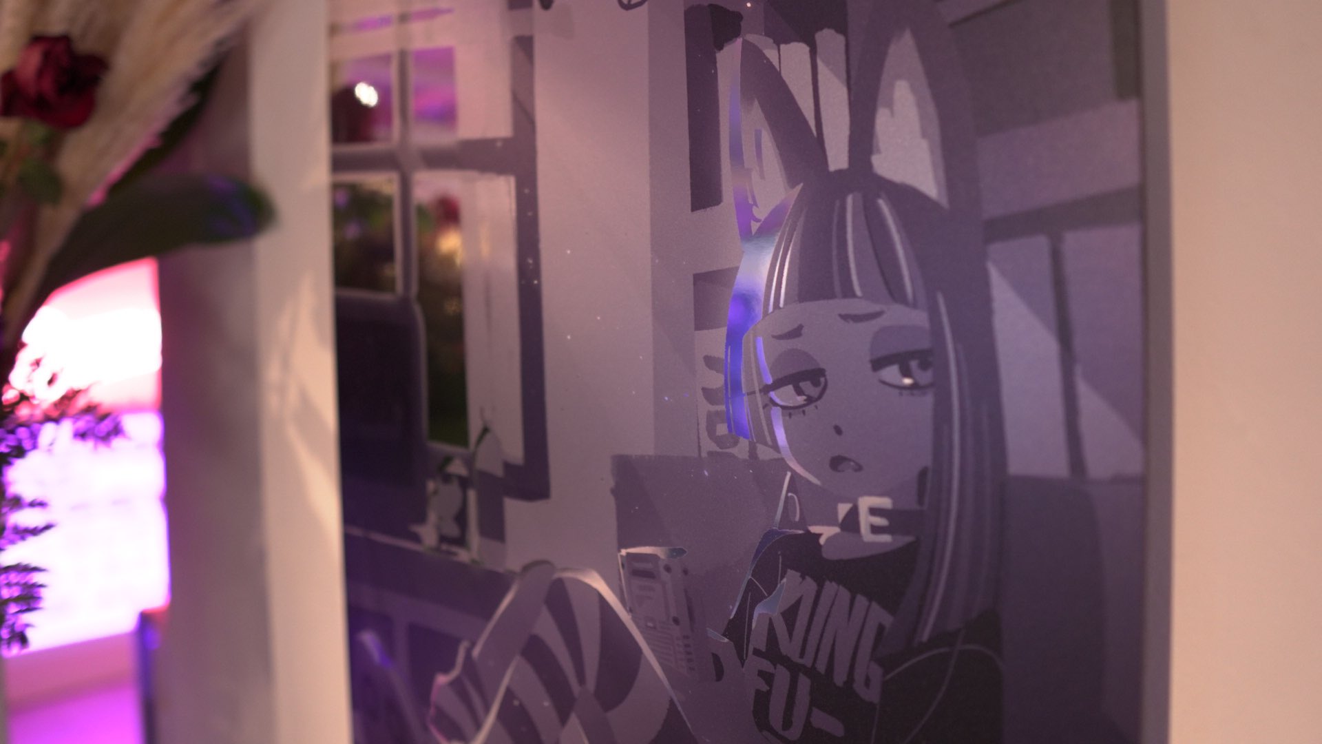 a print of a black and white illustration of a boredlooking anime girl with cat ears. she's wearing a shirt with "king fu" printed on it. the picture is framed and displayed in a gallery setting, illuminated by ambient light.