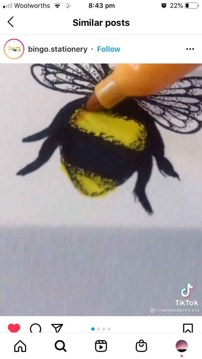 he image shows a closeup video of a hand drawing a bumblebee on a white surface.  the bee is primarily black and yellow. a yellow marker is being used to add color to the bee's body.  the video is from the tiktok account @newmoonprincess and is shared on instagram by the account bingo.stationery. the image includes instagram navigation icons at the bottom.  the top of the image shows the instagram interface, including the name of the account, the time, battery level, and the words "similar posts".