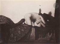 the black and white photograph depicts a couple engaged in a sensual embrace on a bed. the image is largely shadowed, adding to its ambiguous and suggestive nature. the figures are partially nude, with one person's legs visible in stockings.  the bed is covered with a patterned fabric. the overall style is vintage and reminiscent of early to mid20th century art photography, emphasizing mood and suggestion over explicit detail.  the lighting and composition create a sense of privacy and intimacy. the photograph's dark tones and soft focus contribute to an air of mystery.