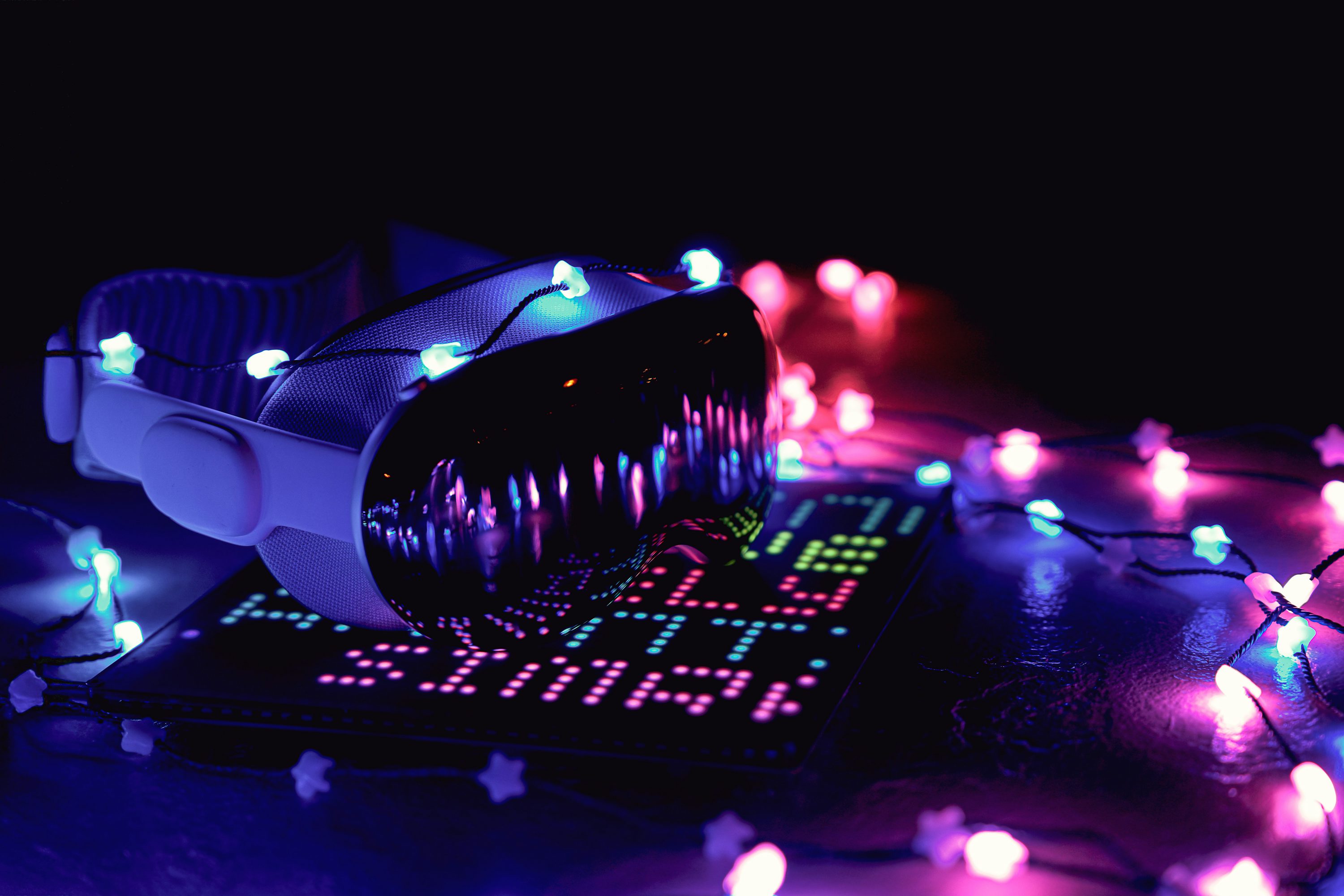 a vr headset sits on top of an led display surrounded by starshaped christmas lights. the scene is set against a dark background with the lights casting a colorful glow.