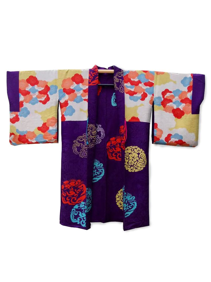 a purple kimono or robe hangs open, featuring a cloud pattern on the sleeves and colorful circular designs on the body. the sleeves are wide and rectangular, typical of kimono design. the body of the robe is a deep purple with various ornate circles in shades of red, yellow, and blue. the sleeves transition from purple to a white background with a repeating pattern of multicolored clouds, including red, yellow, and blue. the overall design suggests a traditional asian garment.
