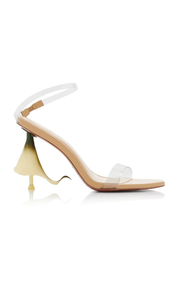 a pair of women's beige high heel sandals with transparent straps are shown. the heel is uniquely designed in a pale yellow, resembling a flower. the shoes appear elegant and stylish, perfect for a special occasion. they are presented against a white background.