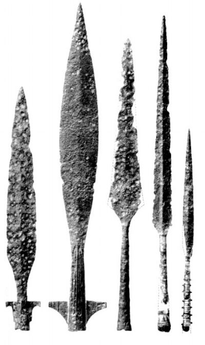 the image shows five different iron arrowheads. each has a distinct shape and size, and they're all displayed vertically against a white background.  the arrowheads are likely archeological finds.