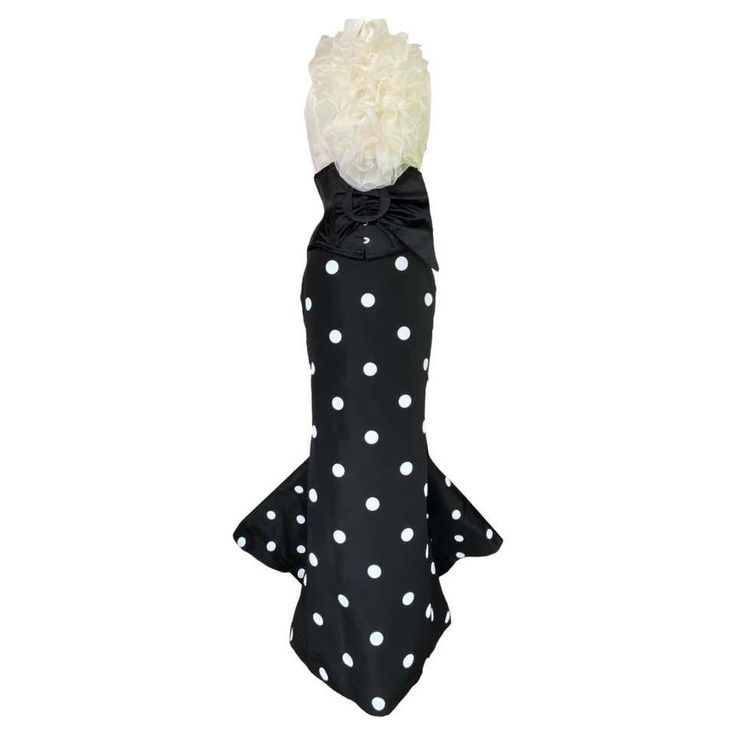 a black and white polka dot dress with a ruffled white top, a bow at the waist, and a mermaid skirt. the dress is a classic and elegant style that would be perfect for a special occasion.