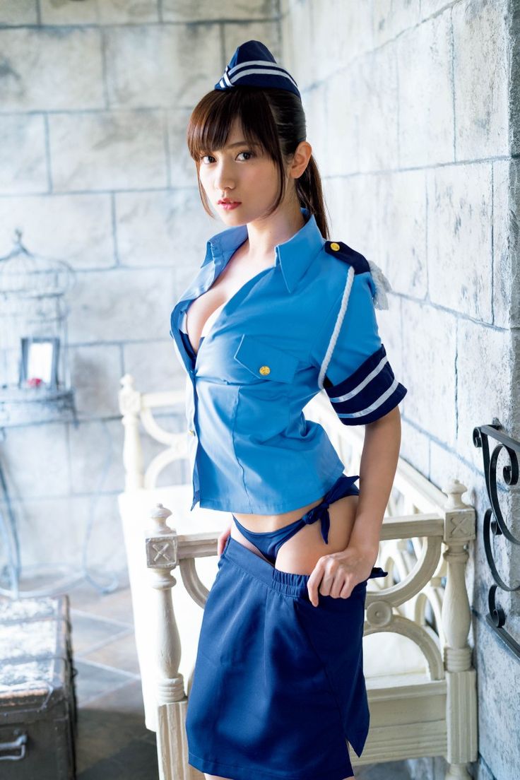 a young, attractive japanese woman in a blue and white flight attendant uniform with a white hat, is standing indoor, posing for the camera, she has her skirt pulled up revealing some of her legs and a dark blue bikini bottom underneath.