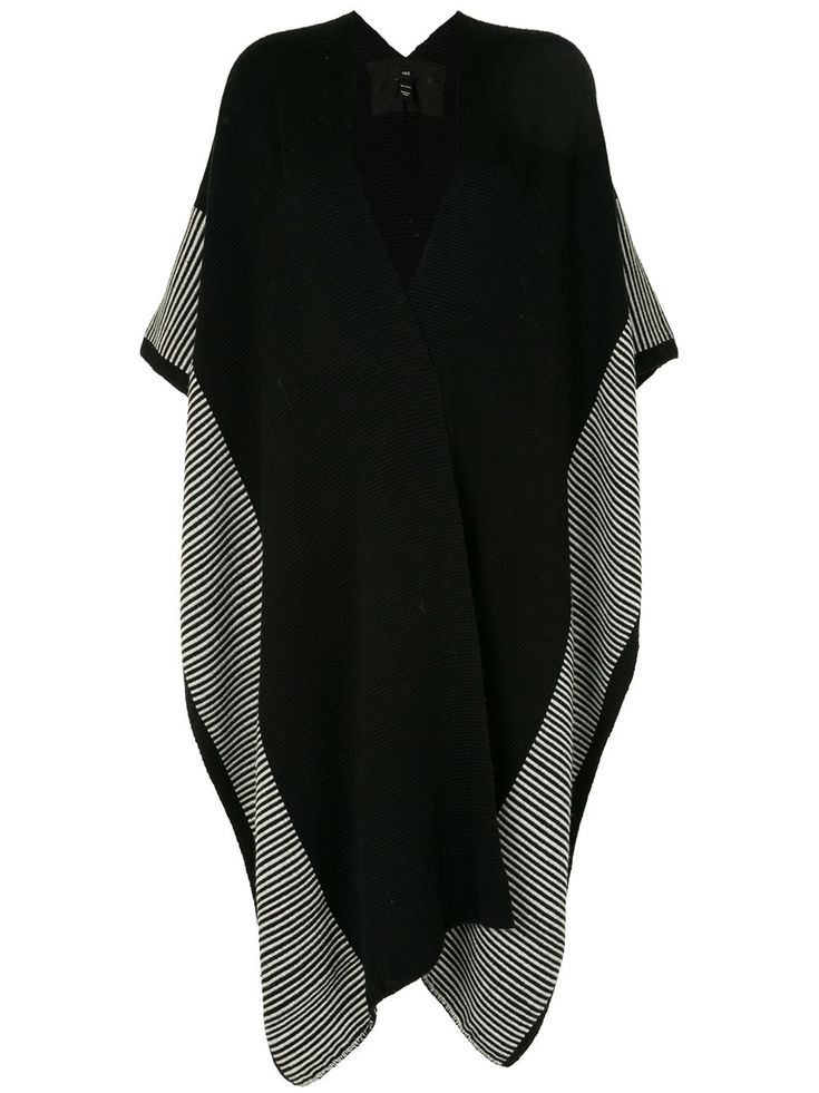 a black knitted poncho with white stripes on the edges. the poncho has a vneck and is made of a soft, cozy knit. it is the perfect layering piece for fall and winter.