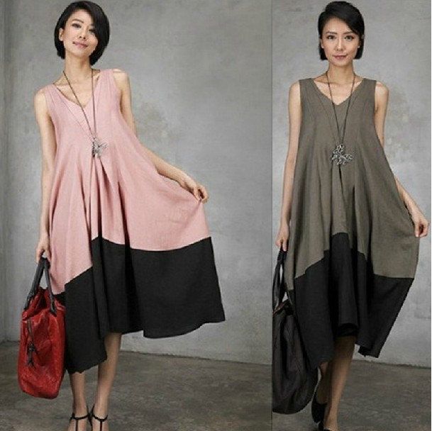 two women are showcased sidebyside, each wearing a twotone, sleeveless dress. the woman on the left wears a pink and black dress with a matching red handbag. she has short hair and a necklace. the woman on the right wears a similar dress in gray and black and carries a black handbag. she also has short hair and a necklace. both women are standing in front of a neutral gray background. the dresses have a vneck cut.