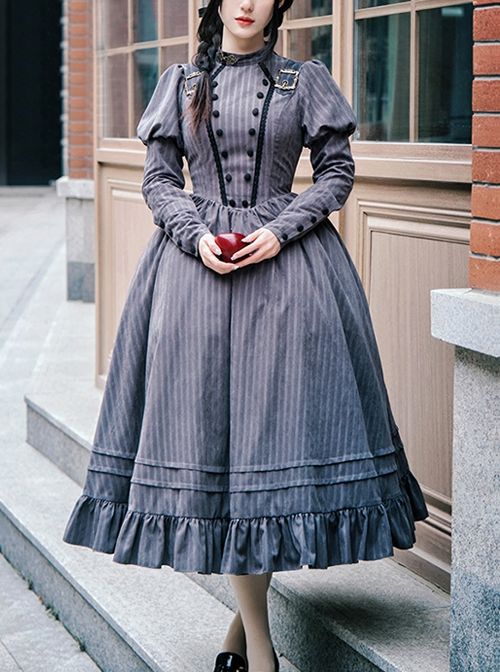 a woman in a longsleeved, gray striped vintage dress is standing on a set of stairs in front of a building. she is holding a red apple in her hands. the dress has a high collar, puff sleeves, and a full skirt with ruffles at the hem. the dress is adorned with buttons down the front and on the sleeves. the woman has her hair pulled back and is wearing minimal makeup. the photo is taken from an eyelevel perspective, and the lighting is natural. the overall tone of the image is romantic and elegant.