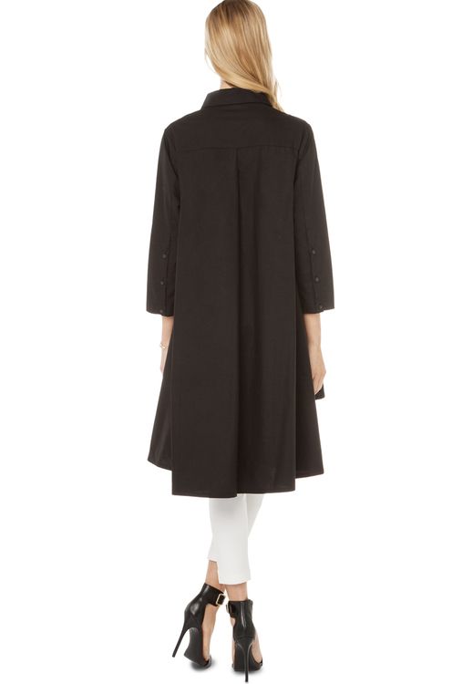 a woman is shown from the back, wearing a black coat. she has blonde hair and is wearing white pants and black highheeled sandals.
