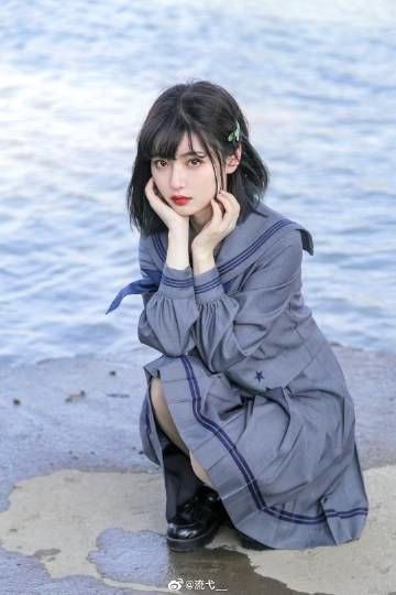 a young asian girl wearing a cute gray sailor school uniform is sitting on