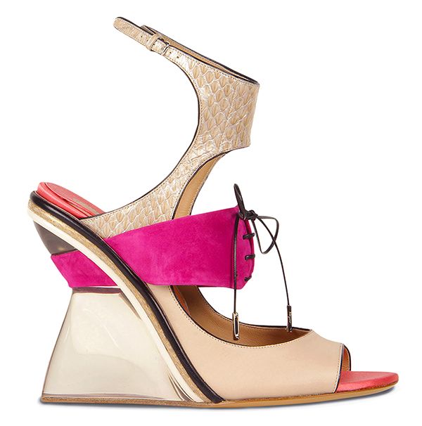 the image shows a pair of women's highheeled sandals. the sandals are a beige color with a pink and gold accent. the heel is a wedge shape, and the sandal has a transparent platform. the shoes have a cutout design and a laceup detail.